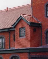 A reroofing project with Plum Red tiles with crested ridges made to match the originals
